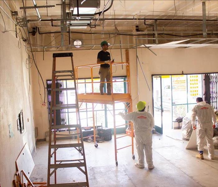 Employees repairing damaged store ceiling. 