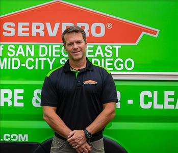 Man standing in front of a green background with SERVPRO logo.