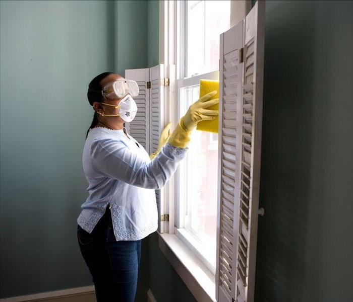Lady cleaning window with goggles and facemask